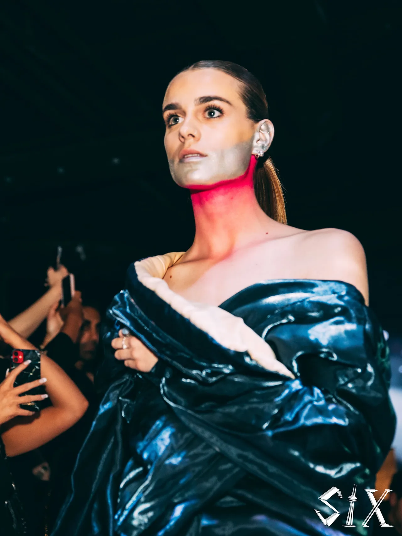 Close portrait of a model with metallic face paint wrapped in a glossy navy puffer.