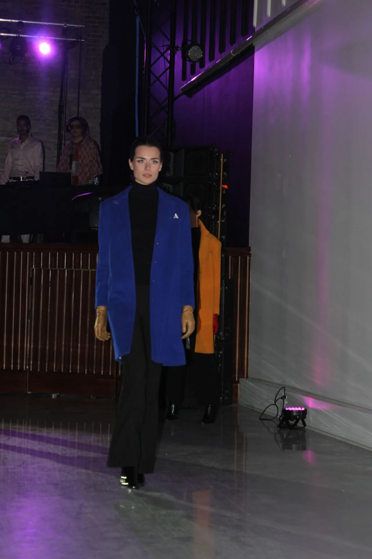A model in a cobalt blue blazer and black flared trousers on the runway.
