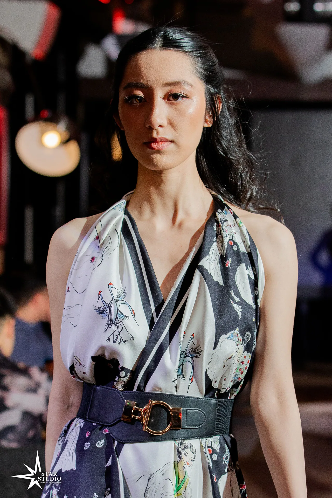 A model in a black-and-white printed halter dress with a wide statement belt.