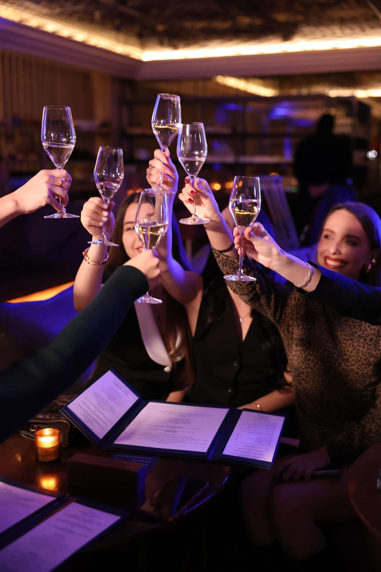 Guests raising champagne glasses in a toast over dinner.