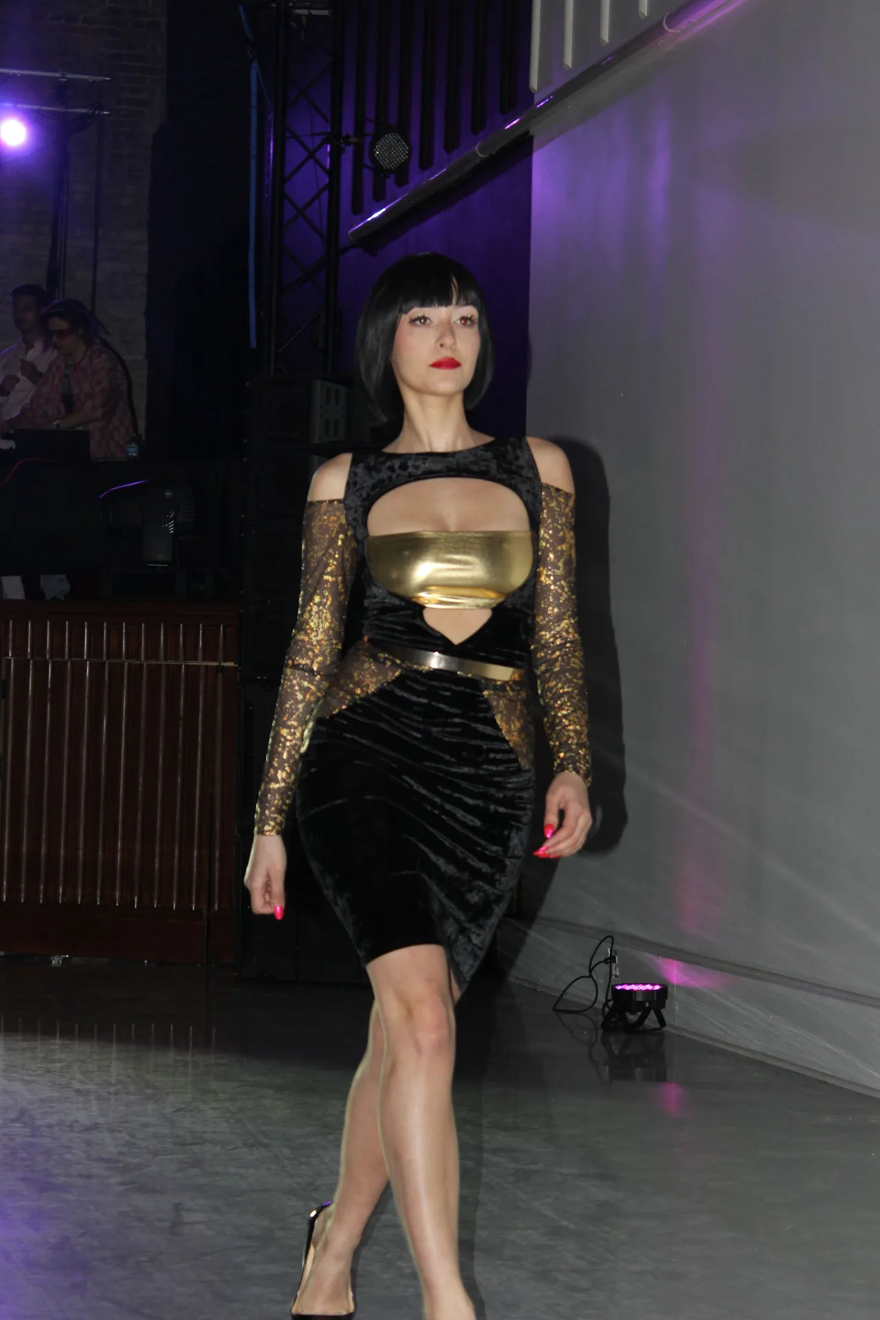 A model in a black dress with a gold cut-out bodice and sheer gold sleeves.