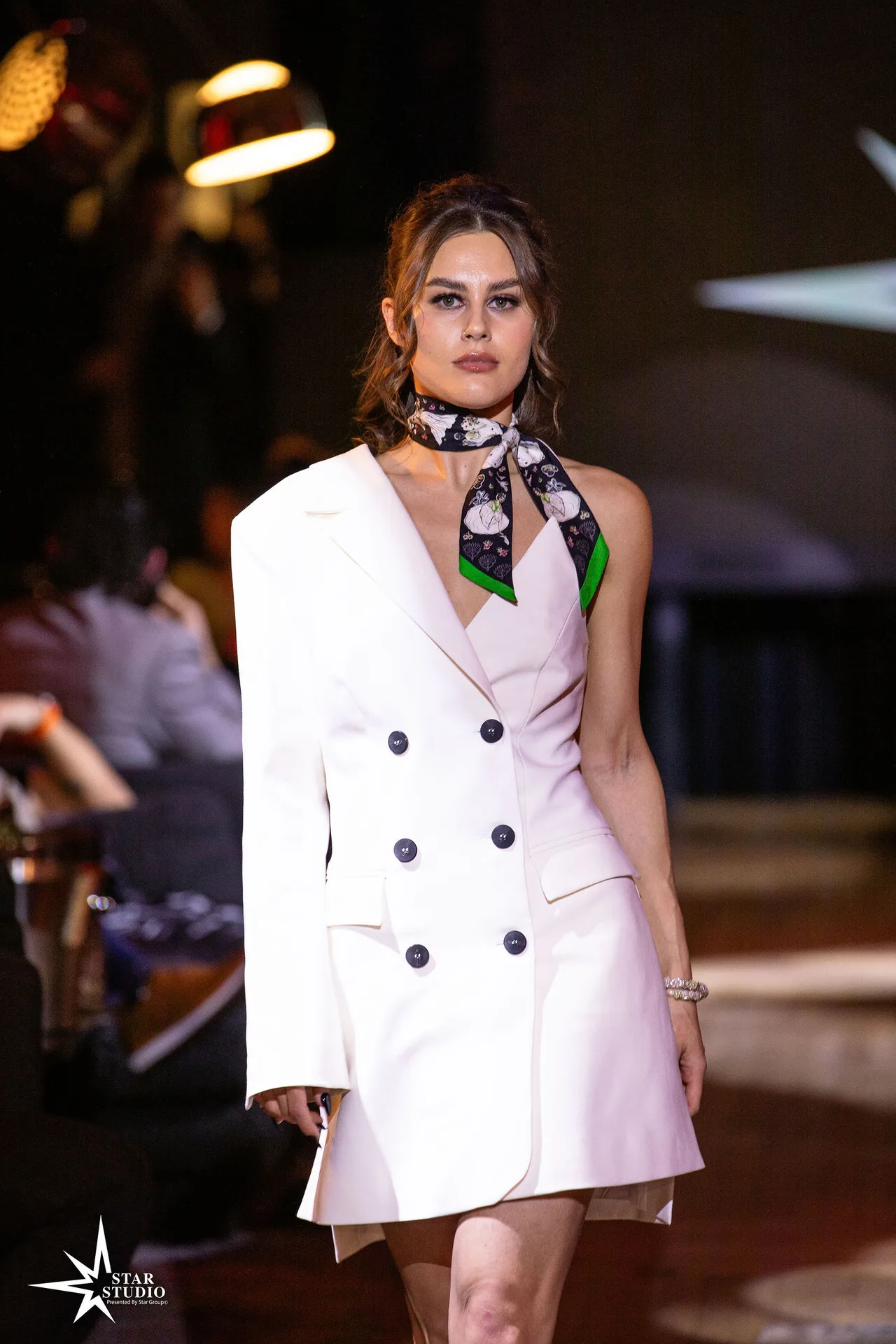 A model in a white double-breasted blazer dress with a printed neck scarf.