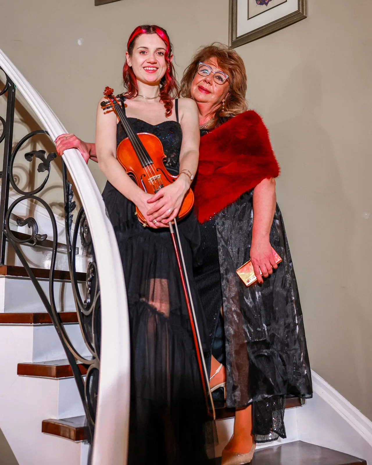 A violinist in black on the curved staircase during the evening.