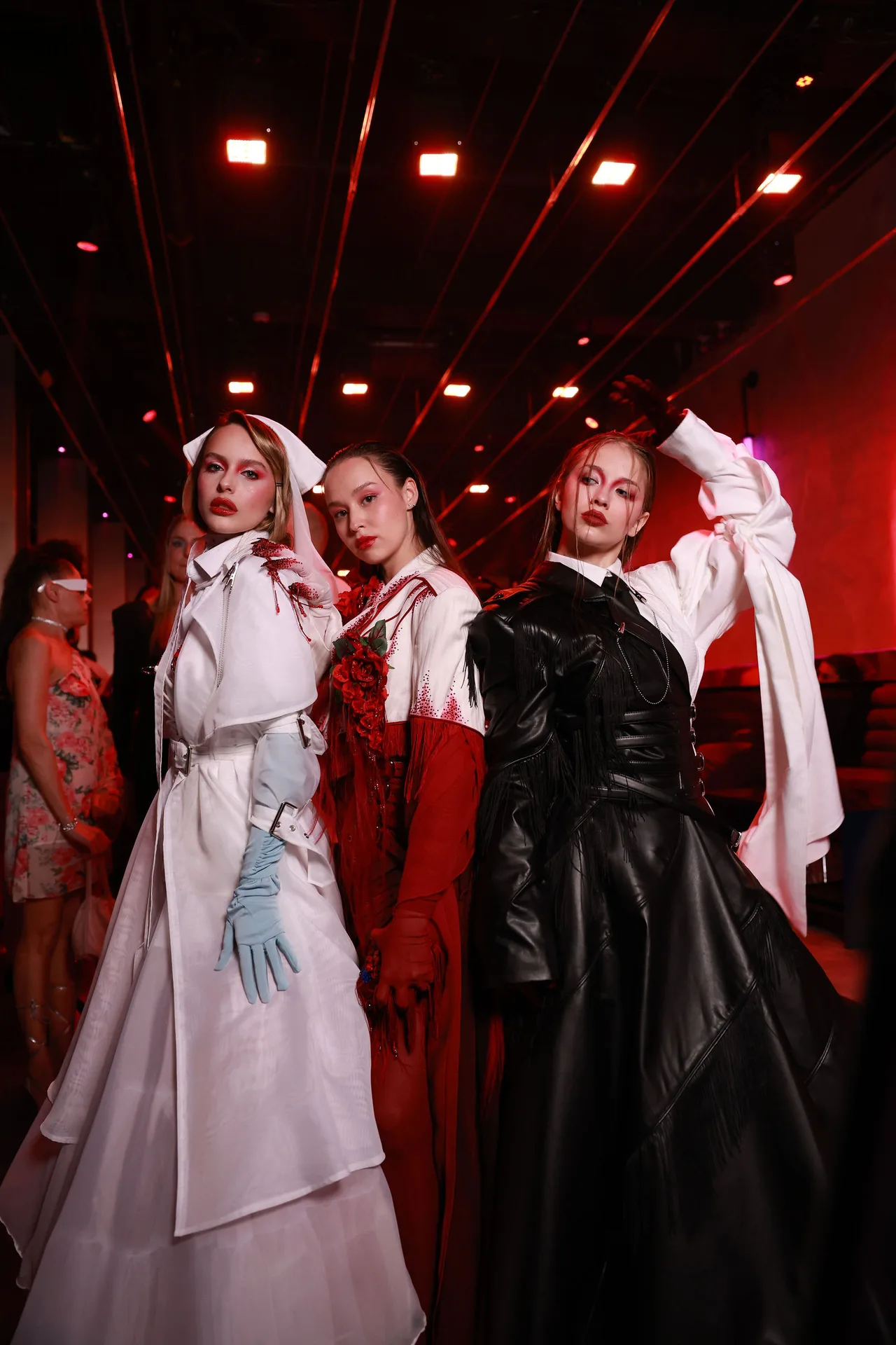 Three models in white, red and black coats together after the show.