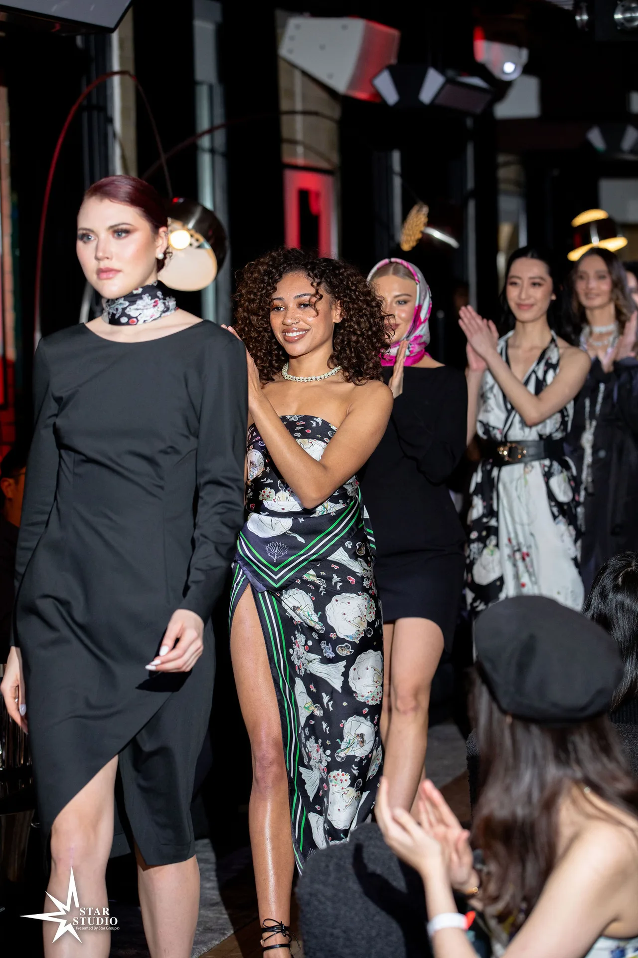 Models on the runway for the finale, applauding.