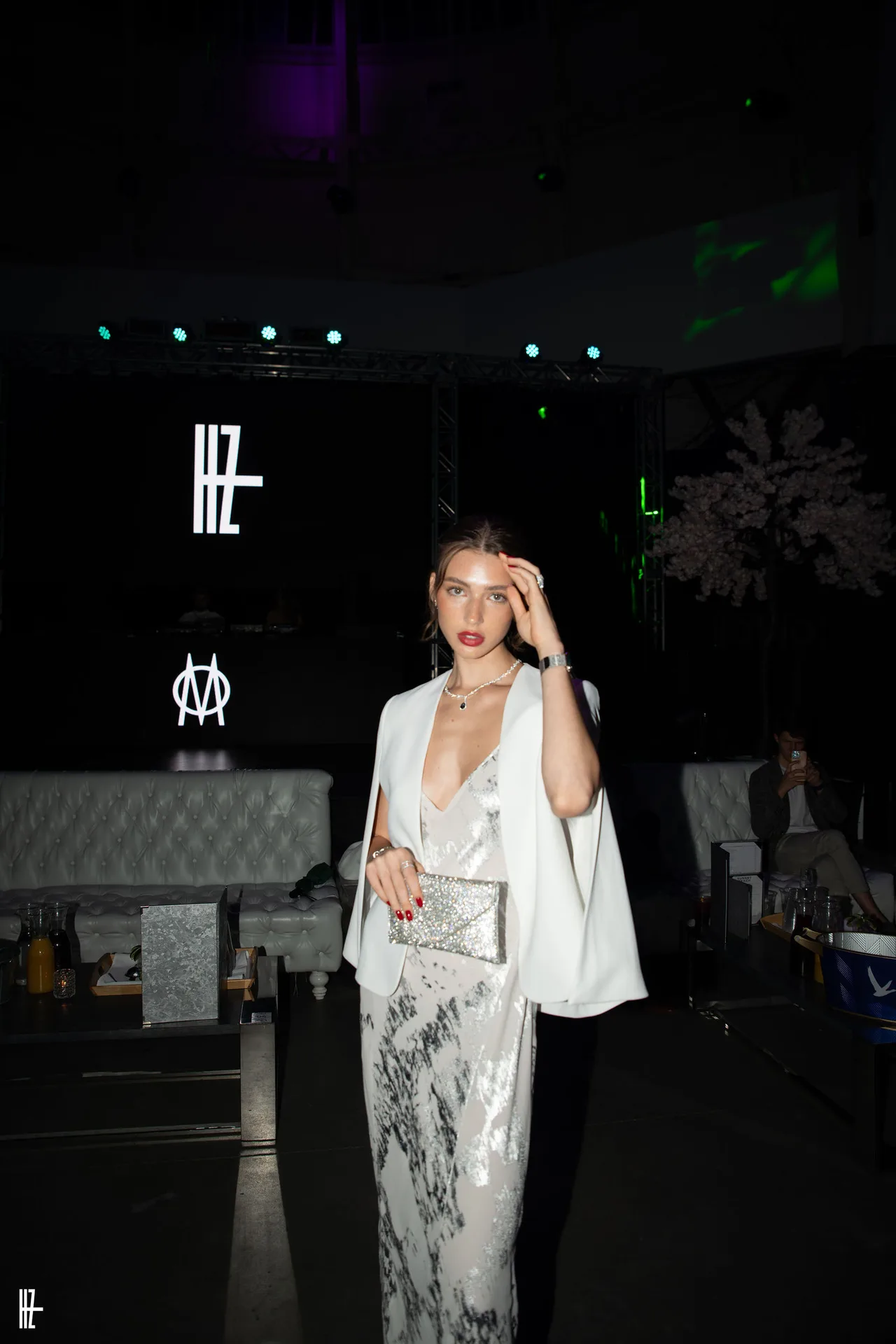 A guest in a silver sequin gown and white blazer at the evening show.