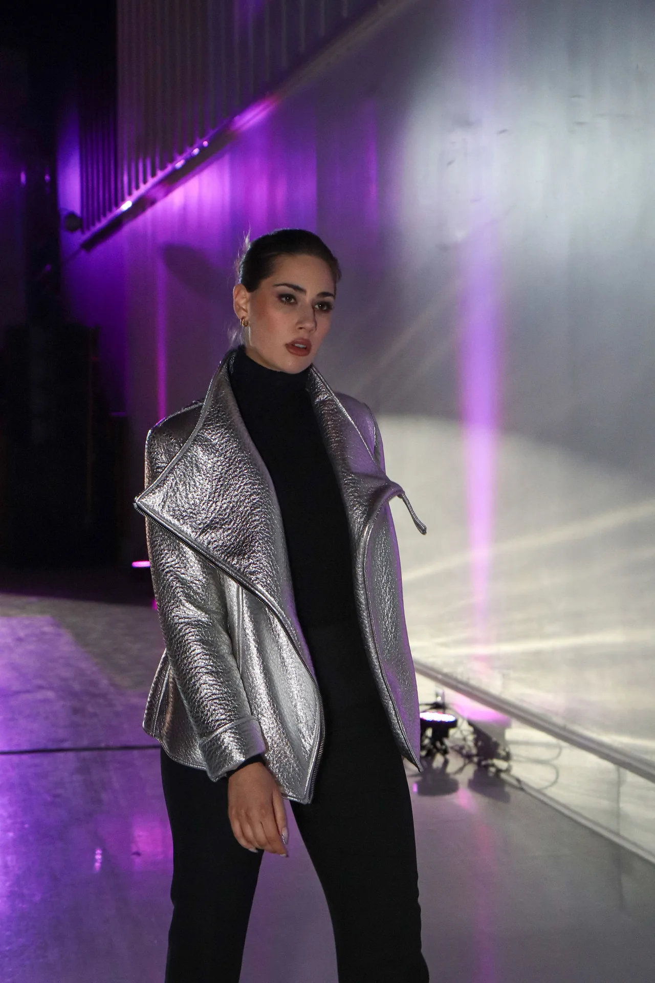 A model in a silver metallic jacket and black turtleneck.