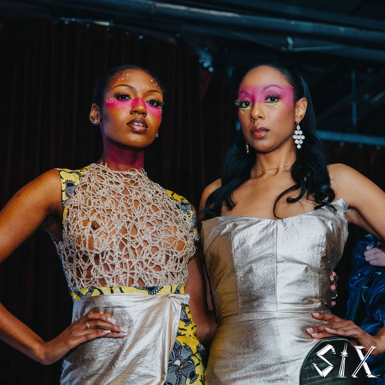Two models in a lace-panelled top and a silver strapless gown with pink eye make-up.