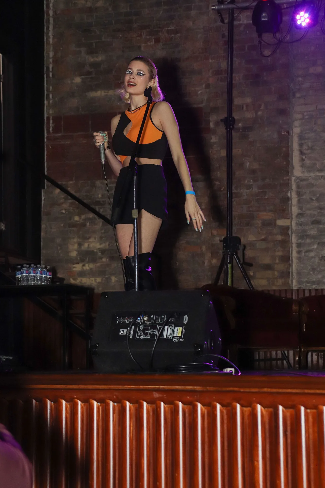 A singer in an orange and black outfit performing on stage.