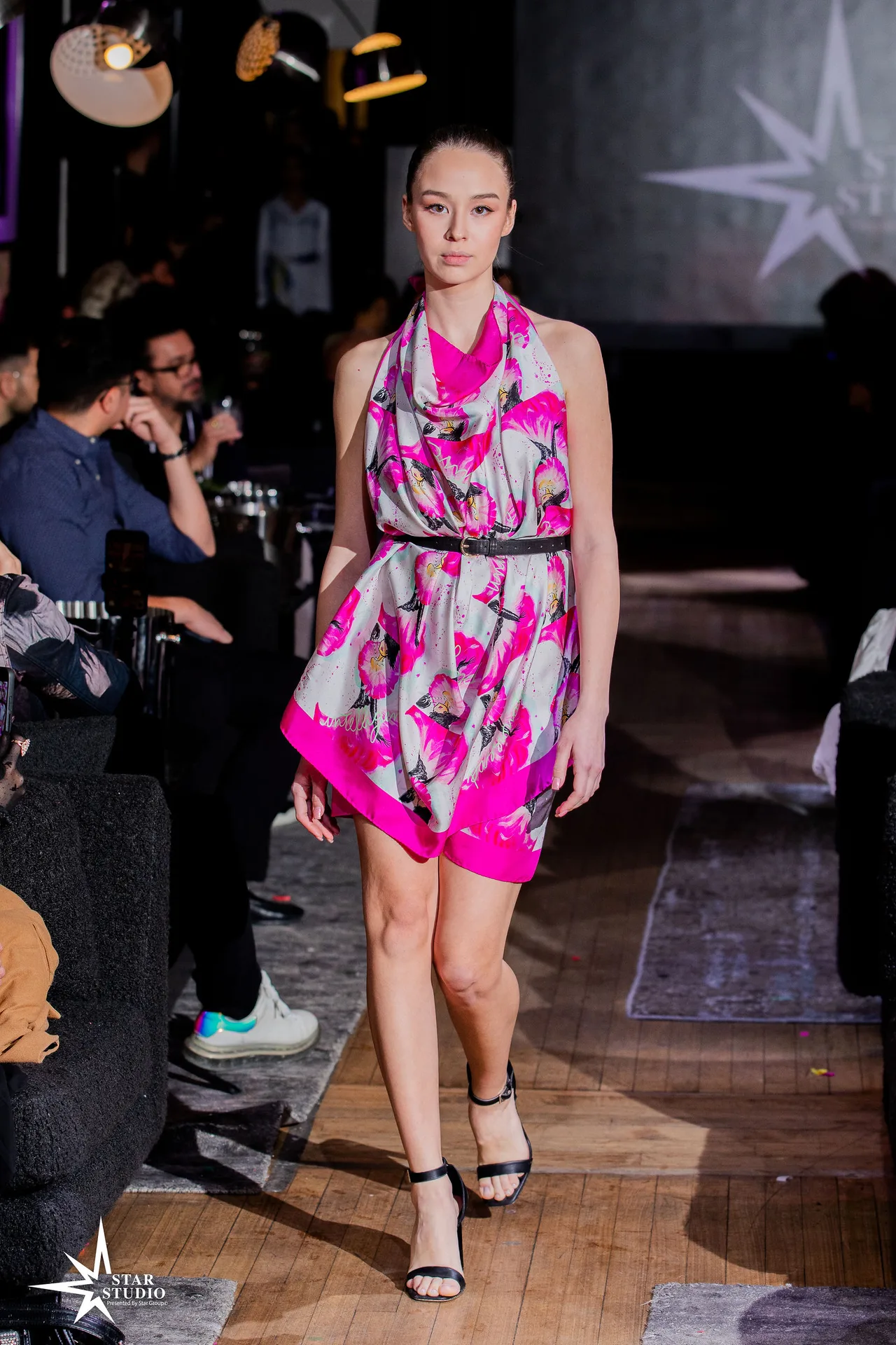 A model in a pink and white floral halter dress walking the runway.